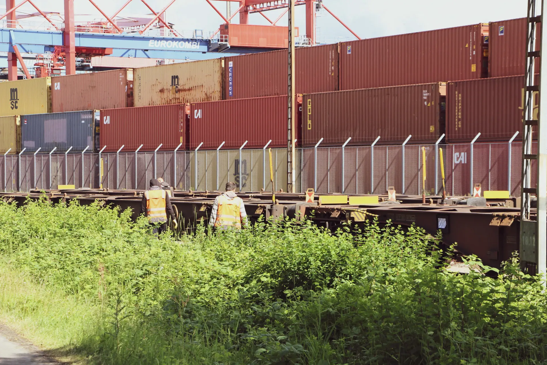 Zwei Arbeiter in Warnwesten gehen neben einem Güterzug